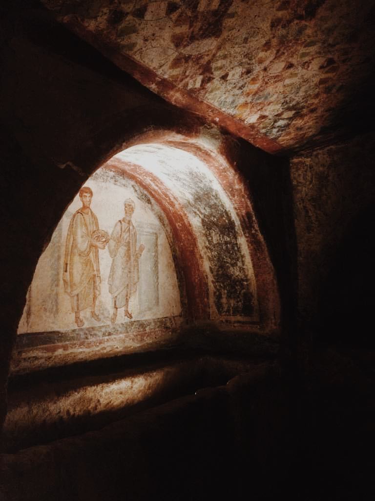 Fresco in an alcove in the San Gennaro catacombs of two men in robes.