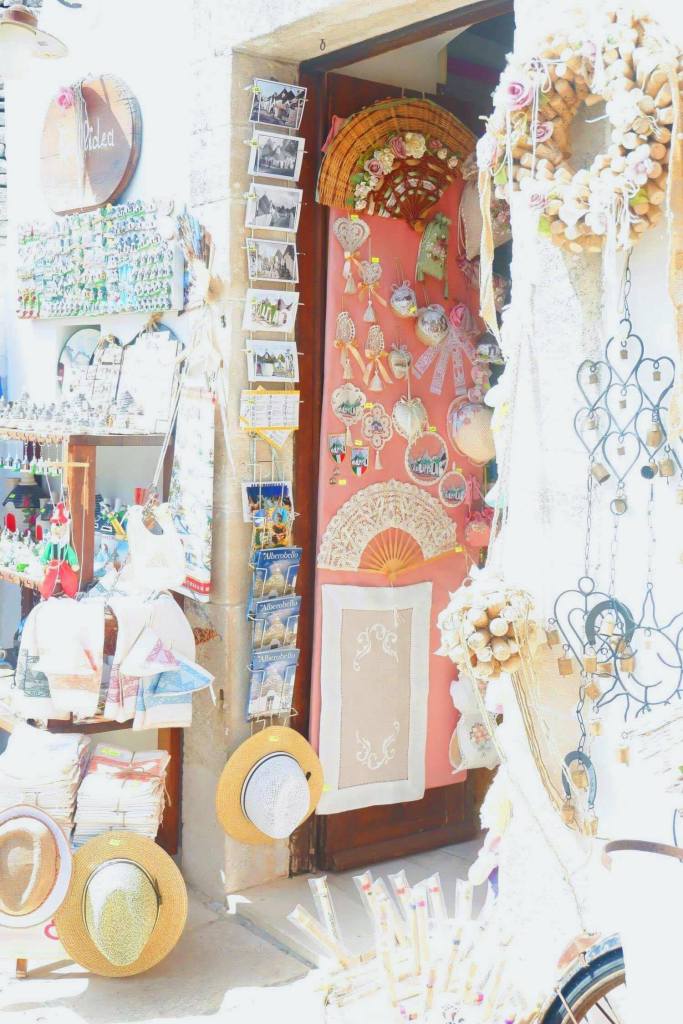 A door of a trulli in Alberobello. the doorway and walls are filled with souvenirs and gifts and post cards. 