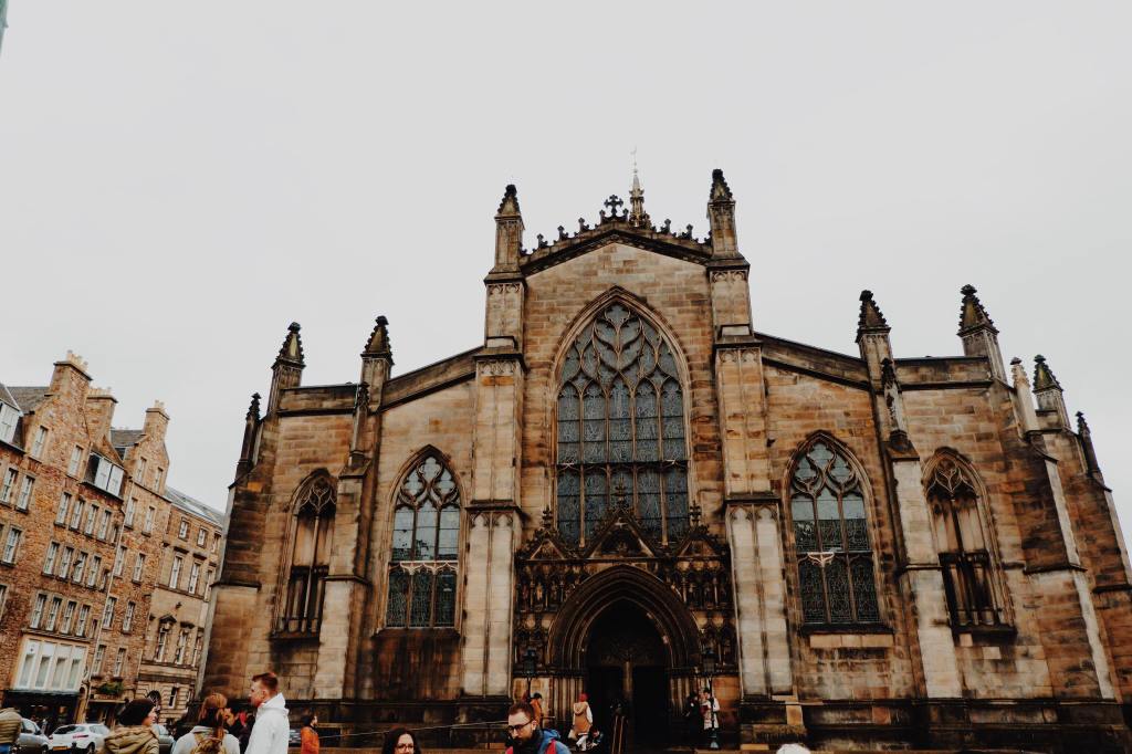 St Giles Cathedral on The Royal Mile. Three stained glass windows and an arched door way with elaborate carvings.