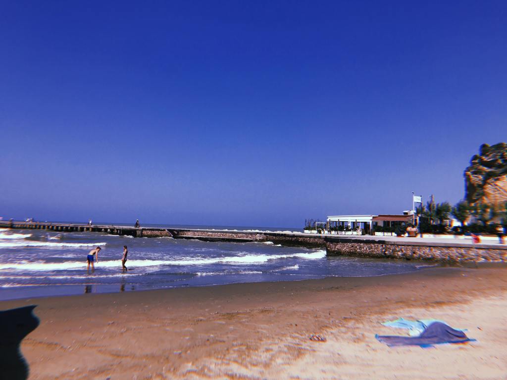 Beach at Torregaveta, sand and sea and a pier extending across the middle of the image